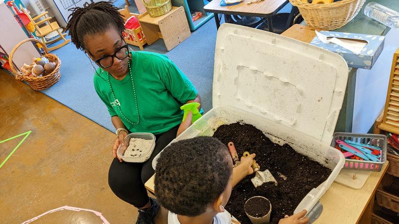 贞洁省长 helps a child plant seeds during a school program