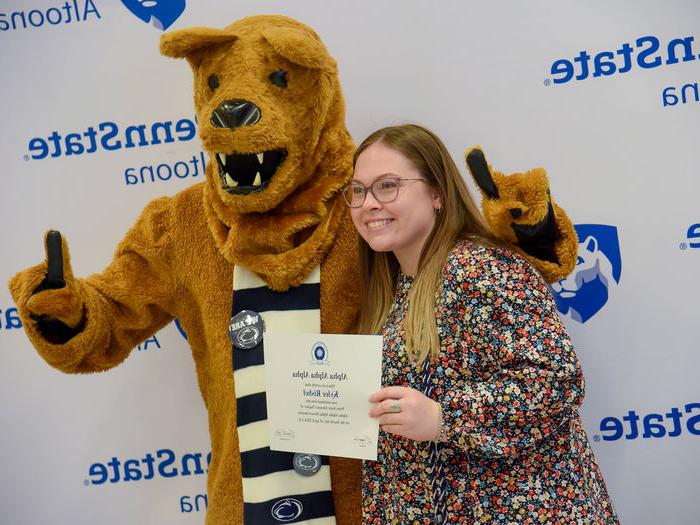 Psychology major Kylee Rishel poses with her certificate and the Nittany Lion after the induction ceremony. 